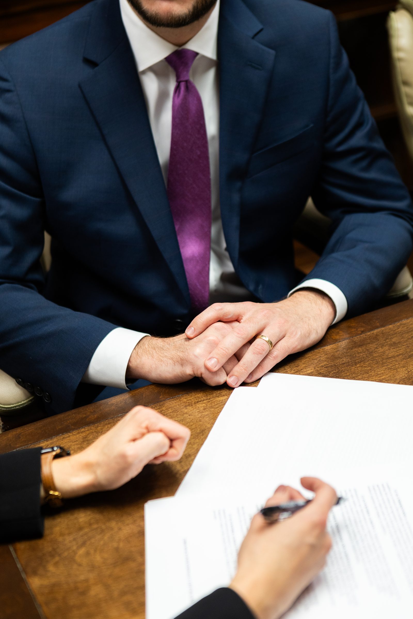 Two people at a conference table with a document and pen between them